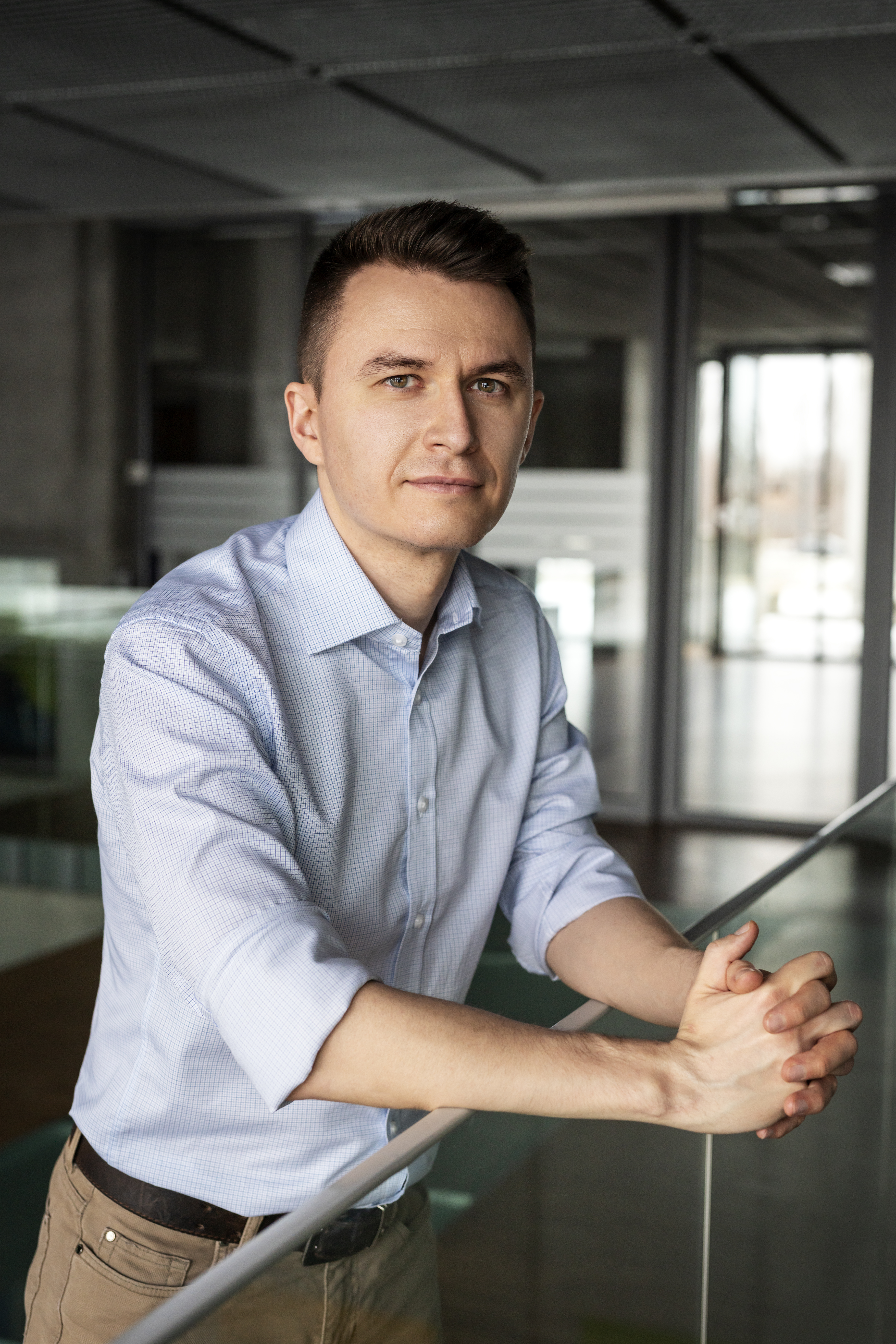 Uśmiechnięty mężczyzna stojący frontem do aparatu z zielonym notesem w ręku