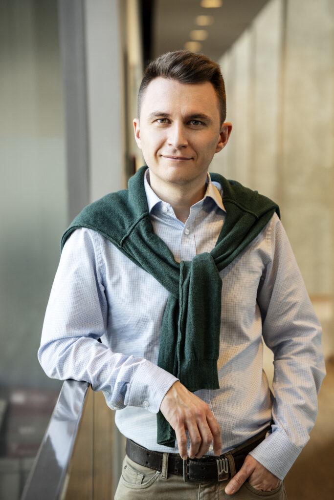 Uśmiechnięty mężczyzna w niebieskiej koszuli z narzuconym na plecy sweterkiem